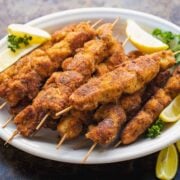 breaded chicken skewers on plate with lemon wedges