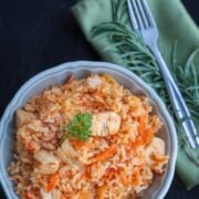 A bowl of Ukrainian chicken plov, rice pilaf, with a green cloth napkin and fork beside the bowl