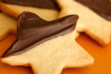 Four chocolate shortbread cookies on an orange plate