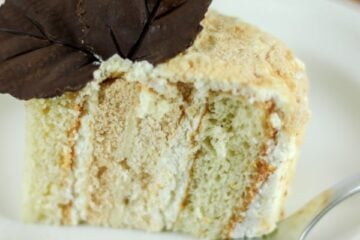 A piece of Kievsky cake on a white plate garnished with two chocolate leaves