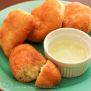 A green with Russian potato piroshki on it and a bowl of garlic dip