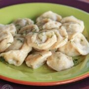 A green plate with Russian pelmeni garnished with dill