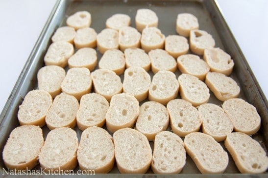 Baguette slices spread on a baking sheet 