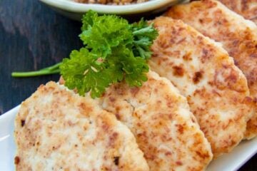 A plate of chicken kotleti lined up in a row with a bowl of buckwheat behind it