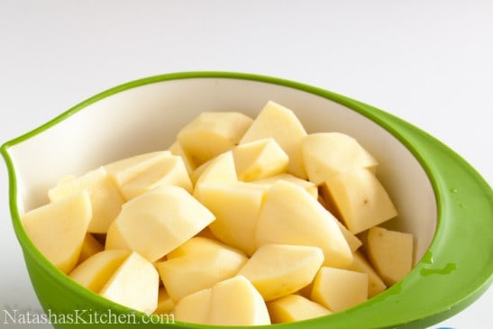 garlic mashed potatoes-11 A green bowl with diced and peeled potatoes