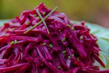 A close up of Mom's creamy beet salad on a green plate garnished with chives