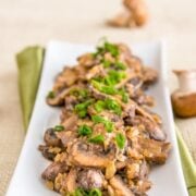 A long plate of mushrooms in a sour cream sauce garnished with green onions