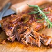 Fall off the bone ribs on a cutting board garnished with rosemary
