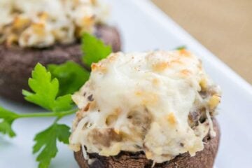 Three chicken stuffed mushrooms in a row on a long plate