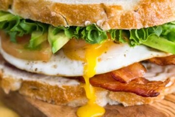 A close up of a breakfast BLT sandwich on a cutting board