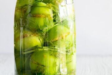 A clear glass jar with pickled stuffed green tomatoes
