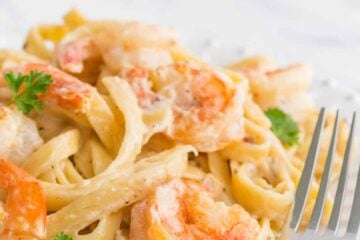 Creamy shrimp alfredo pasta on a plate with a fork beside it