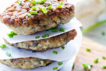 Chicken and mushroom patties stacked with parchment paper between each one garnished with chives