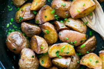 A skillet with crisp saut&eacute;ed red potatoes and a wooden spoon