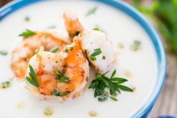 A blue bowl of creamy cauliflower and potato soup with shrimp