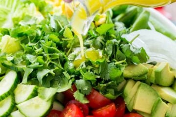A bowl of Mexican salad with a lime dressing being poured over the salad