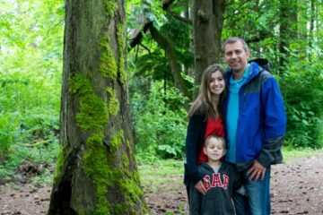 A group of people standing next to a tree in a forest
