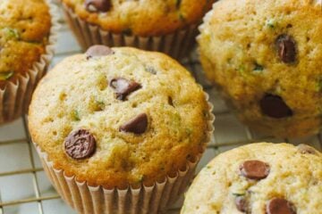 golden zucchini muffins cooling on a rack