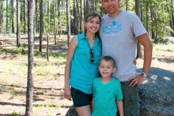 Natasha, her husband and son standing with trees behind them
