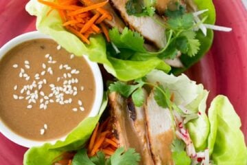 A red plate with Terah's delicious lettuce wraps with a little bowl of sauce beside them