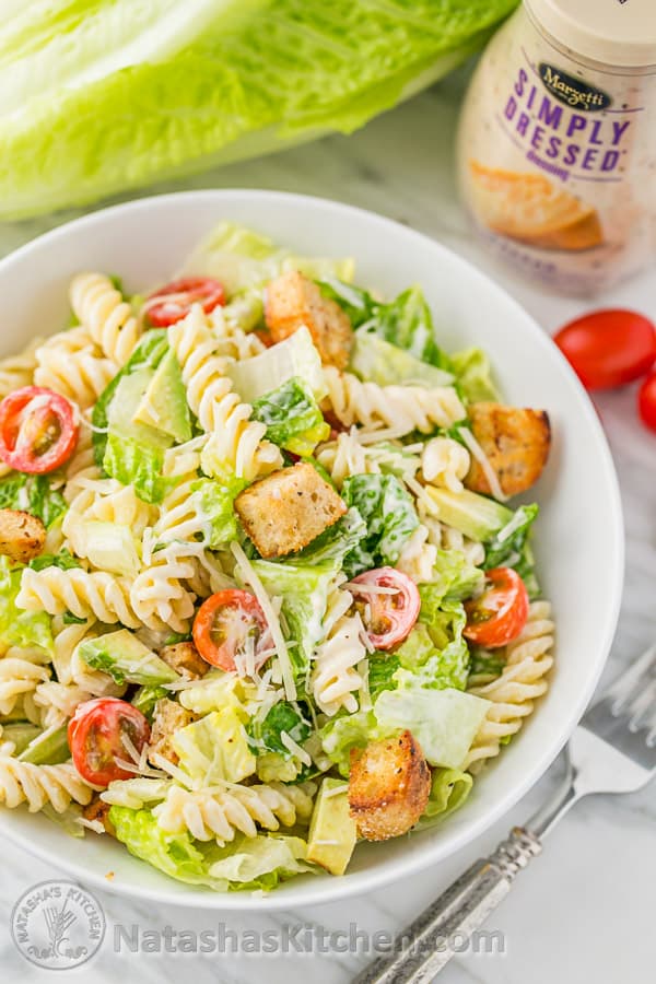 Caesar pasta salad in a bowl with avocado and caesar dressing