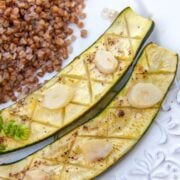 Baked zucchini with garlic and lemon on a plate with buckwheat