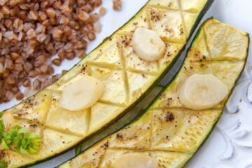 Baked zucchini with garlic and lemon on a plate with buckwheat