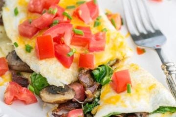 This fluffy egg white omelette is loaded with bacon, mushrooms, cheese, and fresh spinach which softens perfectly inside the omelette. So satisfying! | NatashasKitchen.com