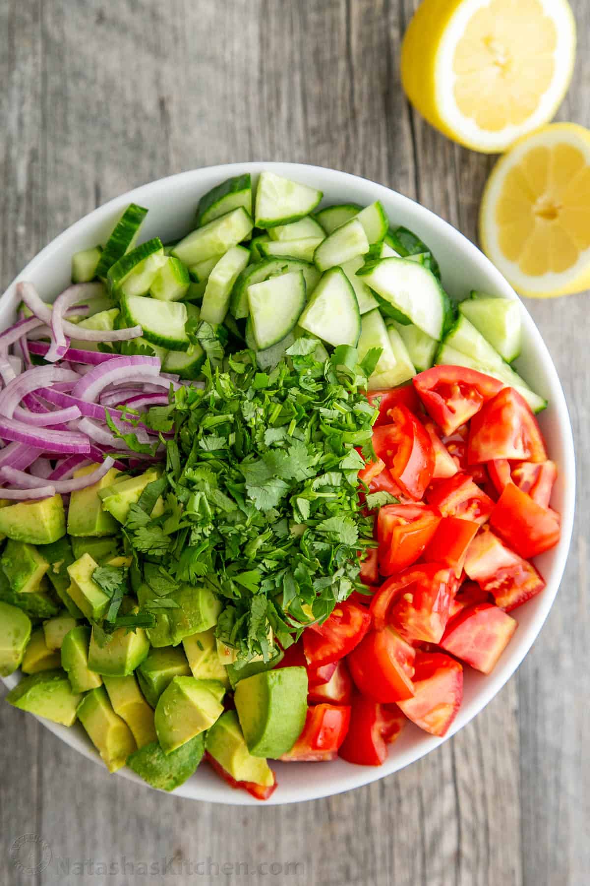 Cucumber tomato and avocado salad chopped in sections in a white salad bowl