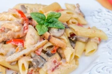 A plate of chicken and vegetable penne alfredo