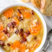 Sauerkraut Soup in a bowl with a spoon beside it and three slices of bread
