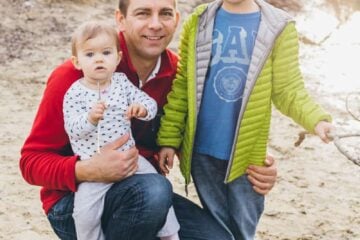 A father and two children standing in the sand