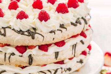 Boccone Dolce has 3 crunchy meringue layers, chocolate, cream and plenty of berries. Drizzled with a berry syrup - this Boccone Dolce Cake is delicious! | natashaskitchen.com