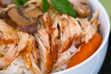 A bowl of slow cooker pulled pork in a mushroom sauce on top of rice