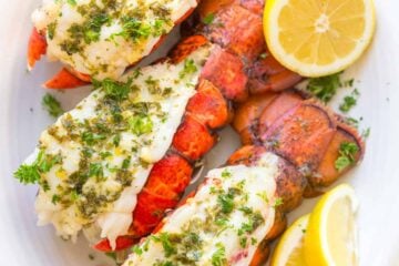 Lobster tails on a serving platter served with lemon wedges