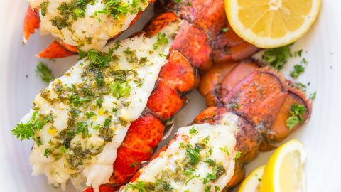 Lobster tails on a serving platter served with lemon wedges