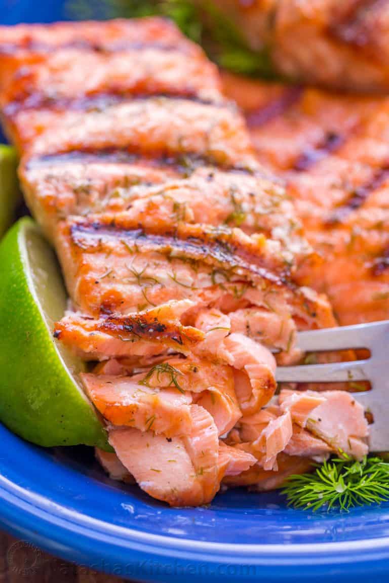 Grilled salmon on a blue plate flaked with a fork
