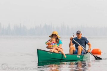 Natasha, her husband, and daughter in a green canoe in a body of water