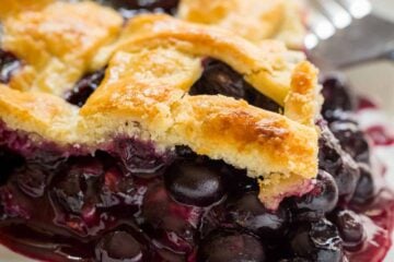 Slice of lattice top blueberry pie on plate