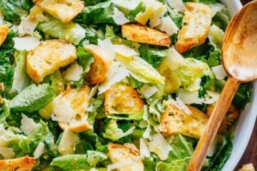 Caesar Salad recipe in a bowl with romaine, croutons, parmesan cheese and caesar dressing