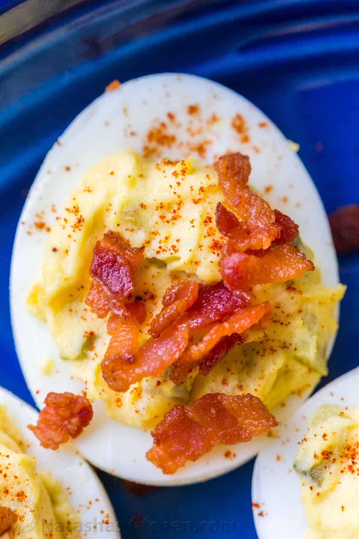 Up close deviled egg served with bacon and paprika garnish