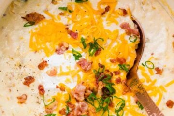 Potato Soup garnished with cheese, chives, bacon and sour cream in a pot