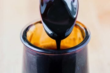 Balsamic glaze pouring off a spoon into jar
