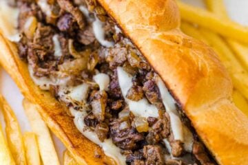 Philly cheesesteak served on hoagie roll with fries and ketchup