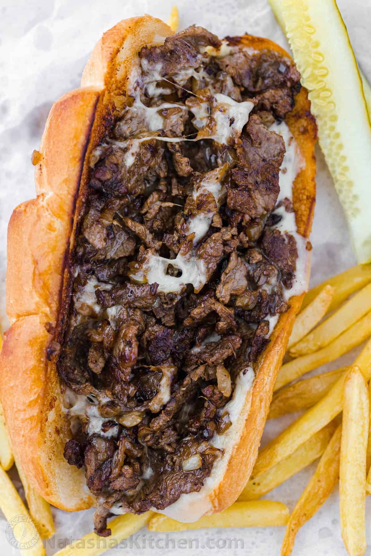 Philly Cheesesteak with tender ribeye steak, melted provolone, and caramelized onion in a garlic butter roll. Easy Philly Cheesesteak Sandwich video how-to. #phillycheesesteak #phillycheesesteakrecipe #phillycheesesteaksandwich #natashaskitchen #cheesesteak #sandwich Philly cheesesteak sandwich with melted provolone cheese