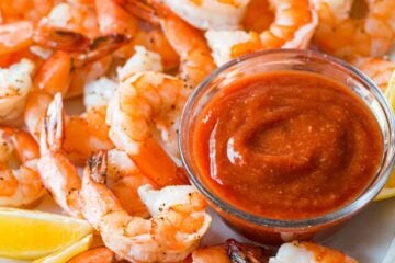Shrimp cocktail with baked shrimp and homemade shrimp cocktail sauce on platter with lemon wedges