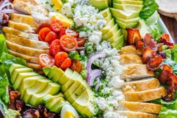 Chicken Cobb Salad on a platter with salad dressing in a mason jar