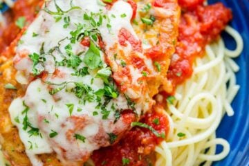 chicken Parmesan served over spaghetti and marinara sauce garnished with basil and parsley