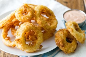 Crisp battered onion rings on white plate