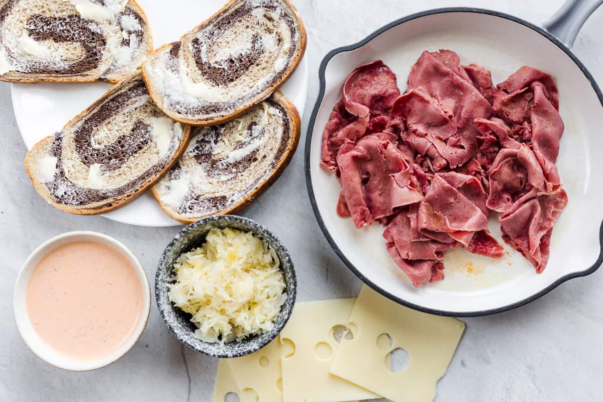 All of the needed ingredients for a Reuben arranged on a board. 